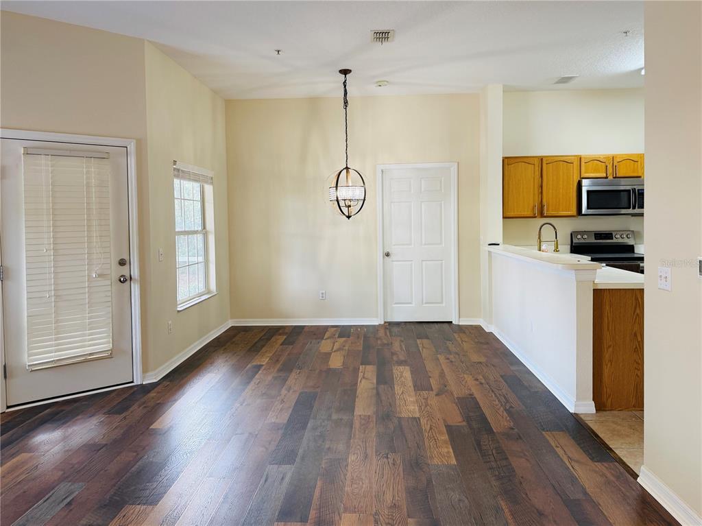 A dining area features wood-look flooring, a pendant light, and an adjacent kitchen with cabinets — 970 N SPRING GARDEN AVENUE UNIT 311, DELAND, FL
