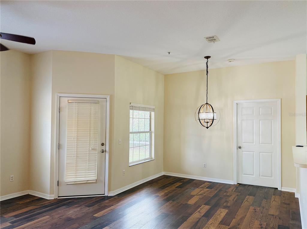 A dining area features dark wood-look flooring, a glass-paneled door, a window, and a chandelier — 970 N SPRING GARDEN AVENUE UNIT 311, DELAND, FL