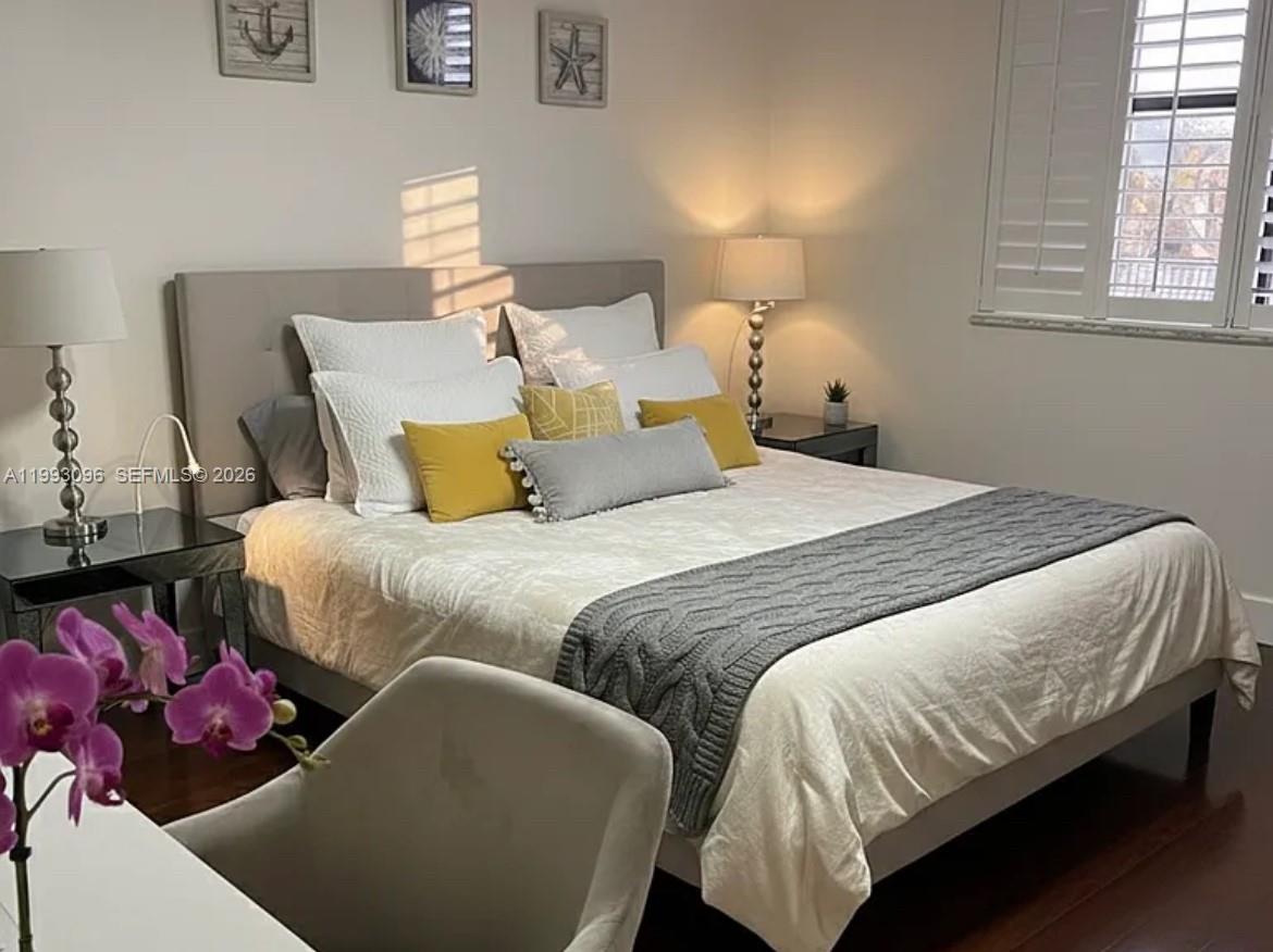 A bedroom features a gray upholstered bed, yellow and gray accent pillows, and two lamps — 2450 NE 135th St # 103, North Miami FL 33181, NORTH MIAMI, FL
