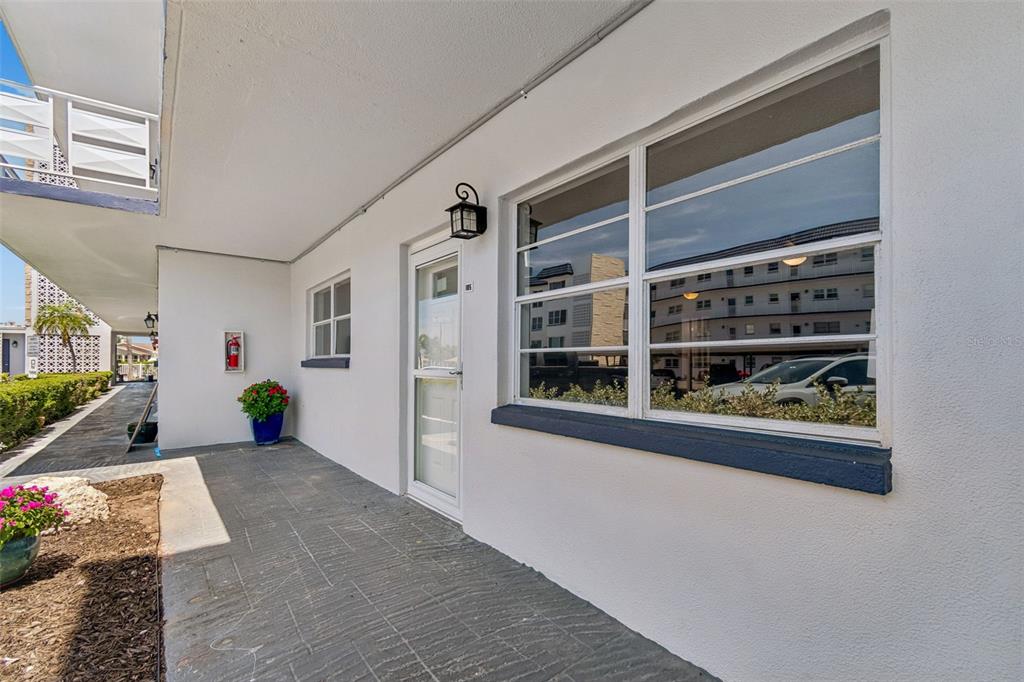 A white exterior wall features a glass-paned door, a large window, and a fire extinguisher — 5955 30TH AVENUE S UNIT 105, GULFPORT, FL
