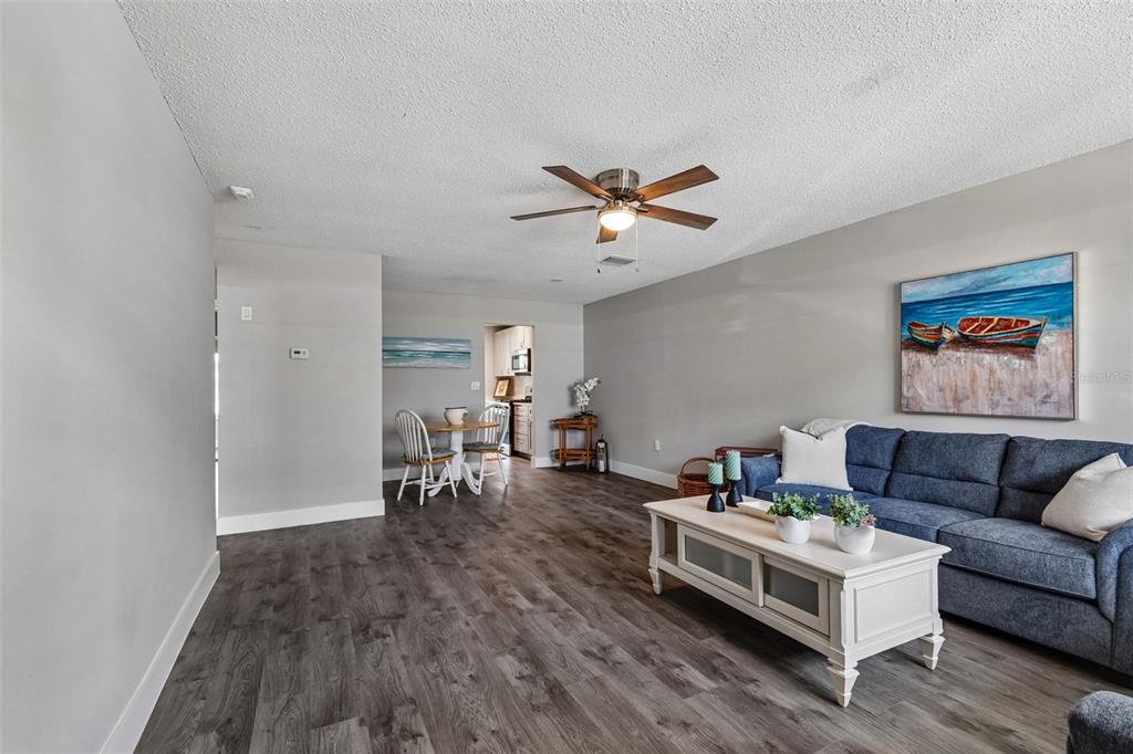 A living room features gray wood-look flooring, a blue sofa, and a white coffee table — 5955 30TH AVENUE S UNIT 105, GULFPORT, FL