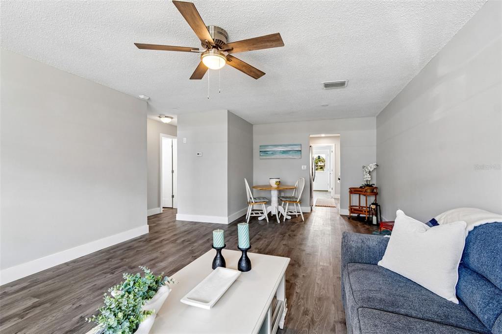 A living room with wood-look flooring, a ceiling fan, and a dining area in back — 5955 30TH AVENUE S UNIT 105, GULFPORT, FL