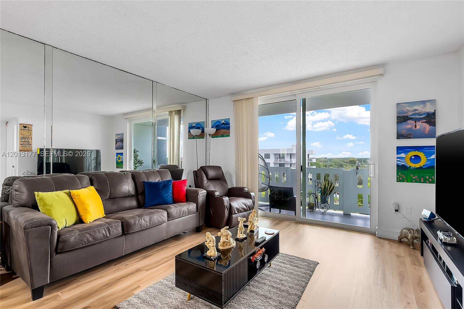 A living room features a brown leather sofa, mirrored wall, coffee table, and balcony access — 919 Hillcrest Dr # 607, Hollywood FL 33021, HOLLYWOOD, FL