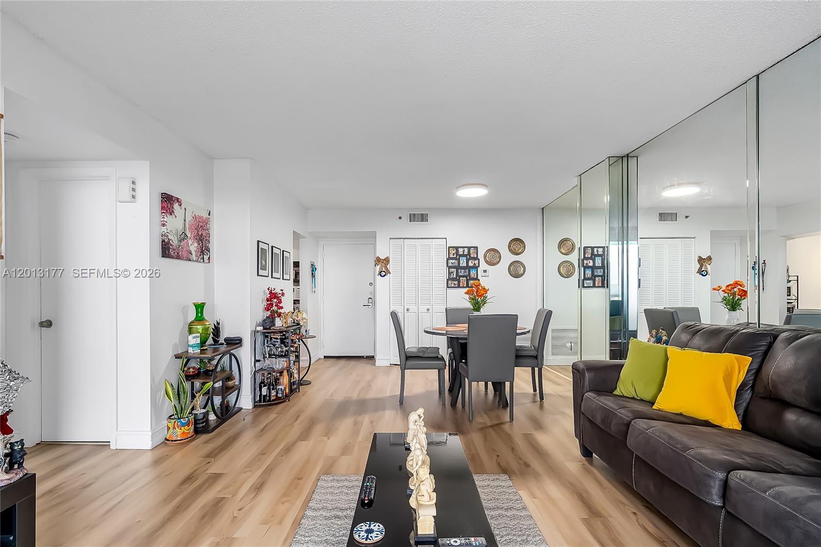 A living and dining area features light wood flooring, a dark sofa, and mirrored walls — 919 Hillcrest Dr # 607, Hollywood FL 33021, HOLLYWOOD, FL