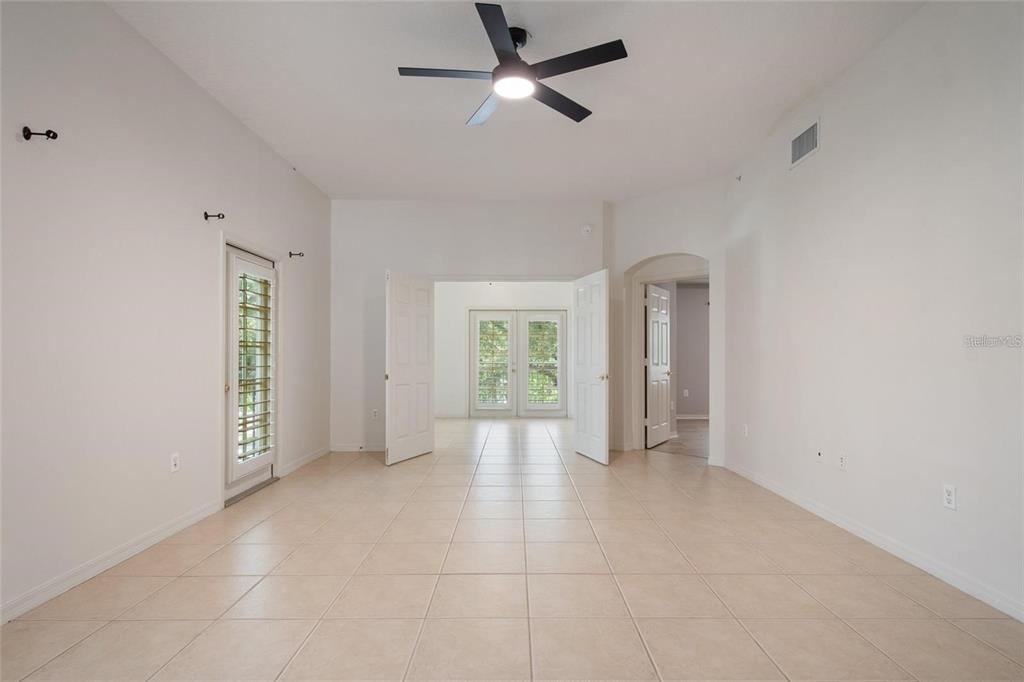 A bright room with beige tile flooring, a ceiling fan, and double doors leading outside — 1007 CELEBRATION AVENUE UNIT 201, CELEBRATION, FL