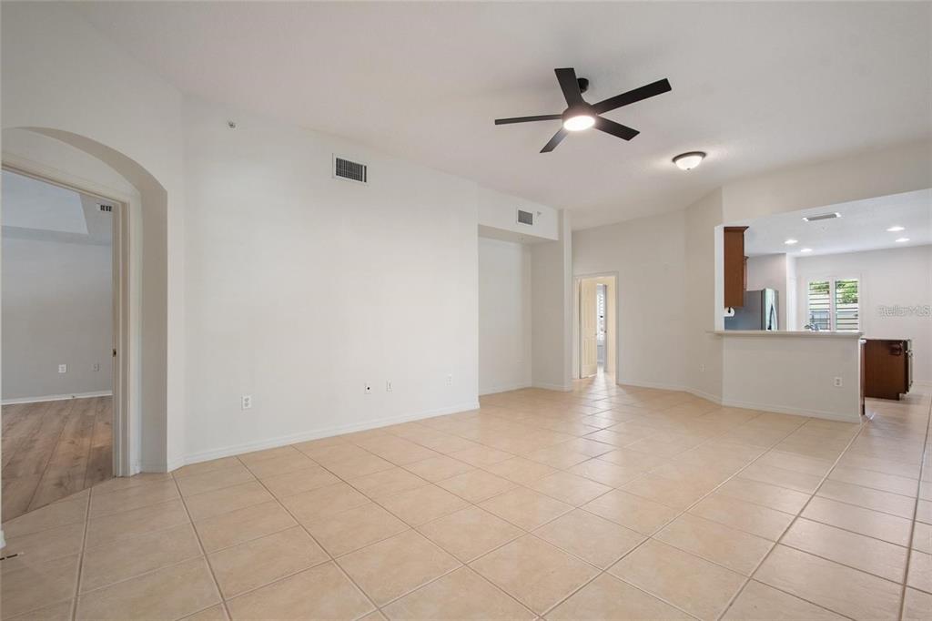 An open-concept living area features light tile flooring, a ceiling fan, and a kitchen pass-through — 1007 CELEBRATION AVENUE UNIT 201, CELEBRATION, FL