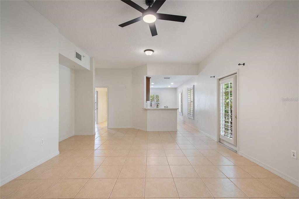 An open-concept living area features light tile flooring, a ceiling fan, and a kitchen pass-through — 1007 CELEBRATION AVENUE UNIT 201, CELEBRATION, FL