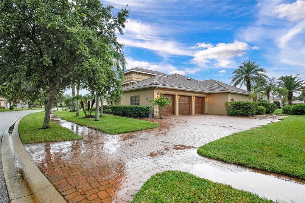 A three-car garage house with a brick paver driveway and lawn in a suburban neighborhood — 3544 TUSCANY RESERVE BOULEVARD, NEW SMYRNA BEACH, FL