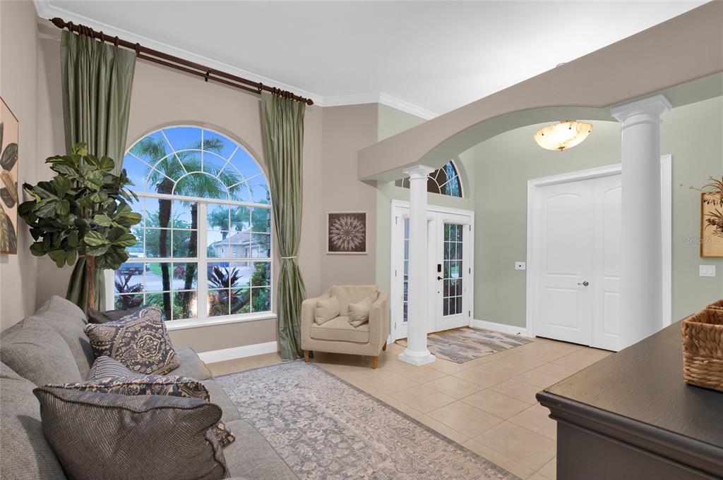 A living room with tile floors, a large arched window, and an arched entryway — 3544 TUSCANY RESERVE BOULEVARD, NEW SMYRNA BEACH, FL
