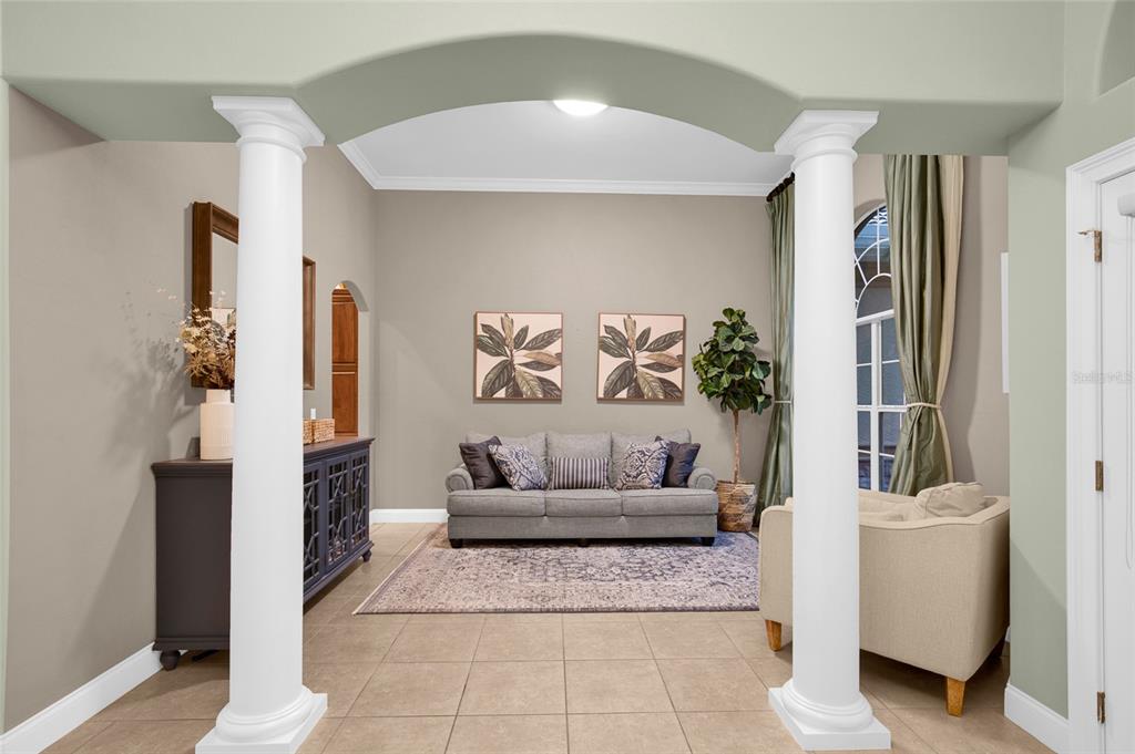 A living room features a gray sofa, two columns, and tile flooring under an arched entryway — 3544 TUSCANY RESERVE BOULEVARD, NEW SMYRNA BEACH, FL