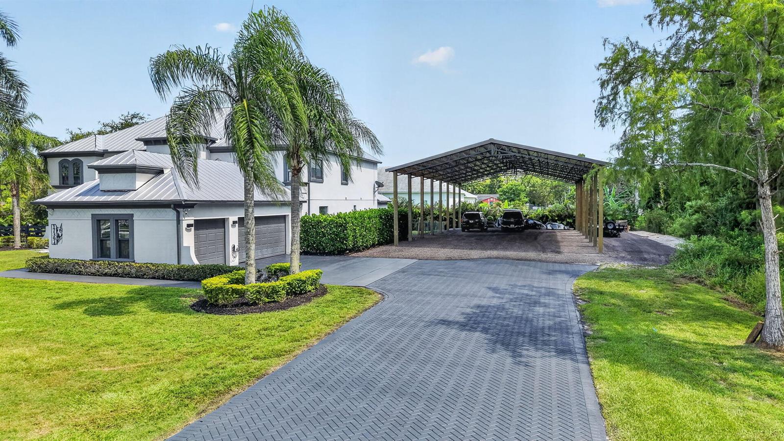 A two-story house with a metal roof, attached garage, and a large metal carport — 17394 Orange Boulevard, FL 33470, FL