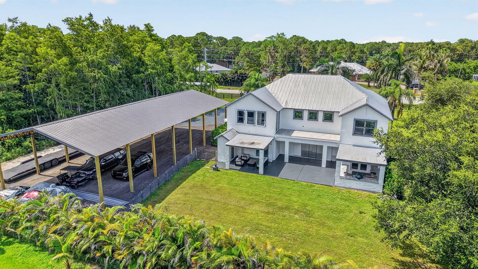 An aerial view of a two-story house with a metal roof and a large carport — 17394 Orange Boulevard, FL 33470, FL