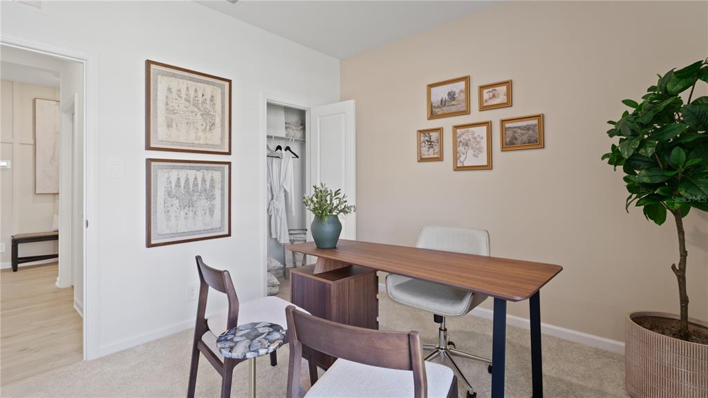A home office features a wooden desk, two chairs, a closet, and framed wall art — 5215 HAVEN VIEW DRIVE, CLERMONT, FL
