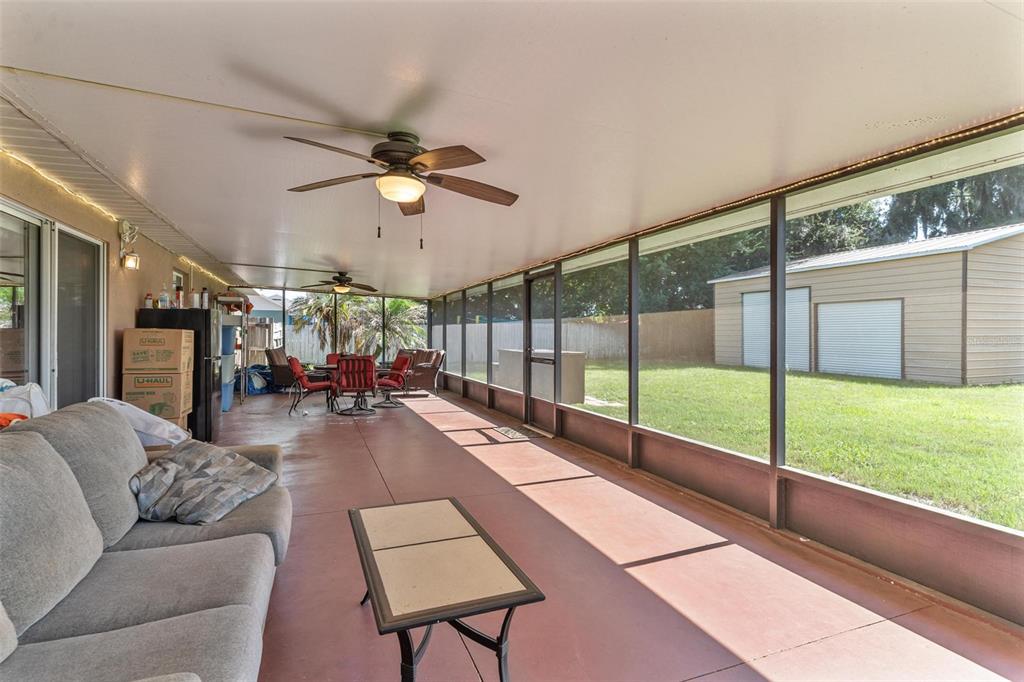 A screened-in patio features a concrete floor, ceiling fans, and a view of a backyard — 200 WATERS EDGE DRIVE, LEESBURG, FL