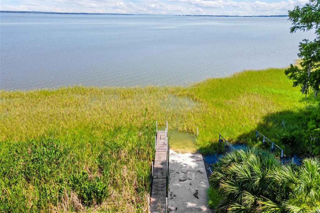 An aerial view shows a concrete boat ramp and wooden dock extending into a lake — 200 WATERS EDGE DRIVE, LEESBURG, FL