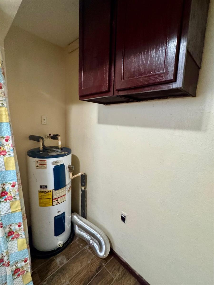 A water heater sits in a utility room with dark wood cabinets and tile flooring — 714 S Seminole Avenue, FL 33841, FL