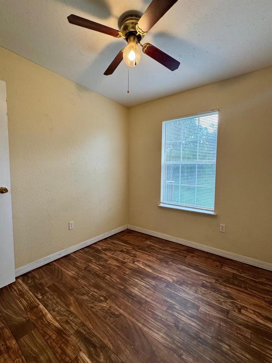 An empty bedroom features light yellow walls, wood-look flooring, and a ceiling fan — 714 S Seminole Avenue, FL 33841, FL