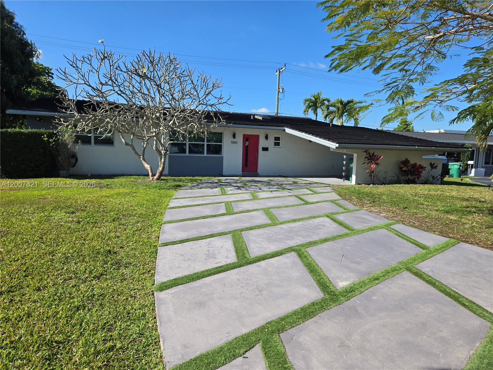 A single-story house features a red front door and a modern concrete paver driveway — PALMETTO BAY, FL