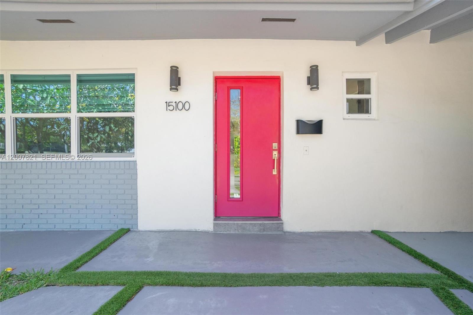 A bright pink front door is centered on a white exterior wall with a window — PALMETTO BAY, FL