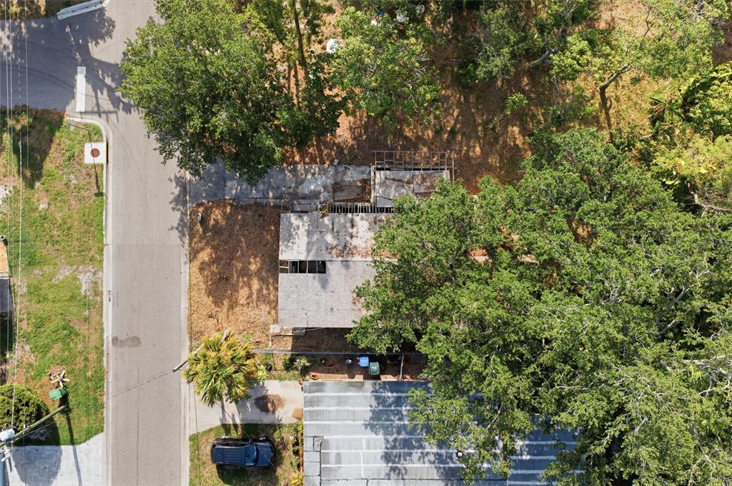 An aerial view shows a residential property with a damaged roof and surrounding trees — 202 12TH AVENUE E, BRADENTON, FL