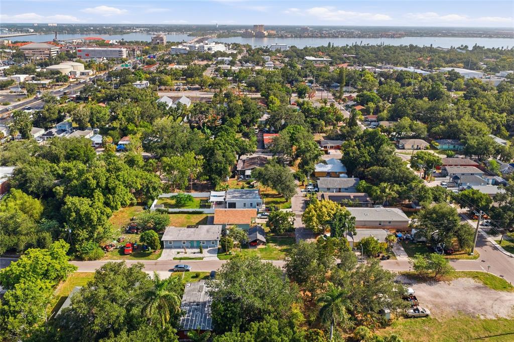 An aerial view shows a residential neighborhood with houses, dense trees, and a distant waterfront — 202 12TH AVENUE E, BRADENTON, FL