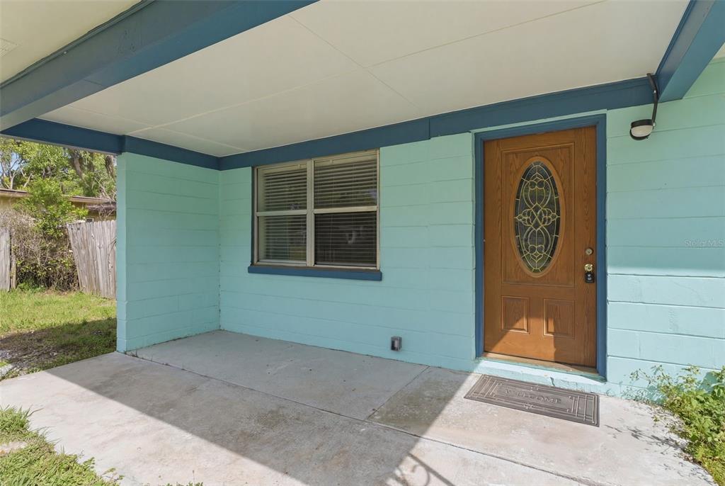 A covered concrete porch leads to a wooden front door with an oval glass insert — 27 CROOM ROAD, BROOKSVILLE, FL