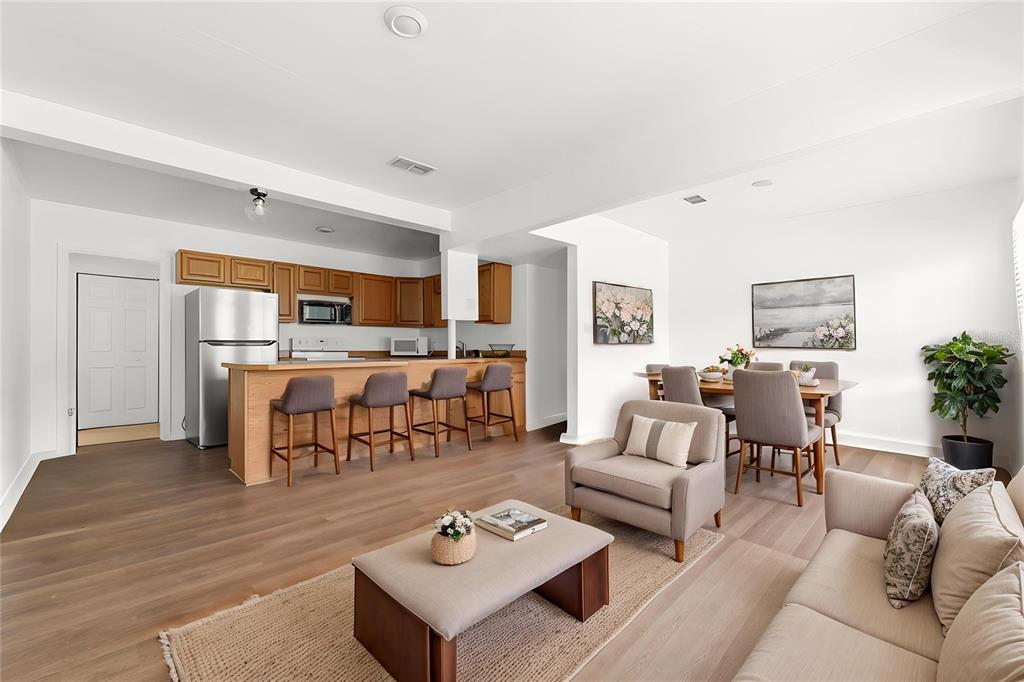 An open-concept living and dining area features wood-look flooring, a kitchen island, and neutral furniture — 27 CROOM ROAD, BROOKSVILLE, FL