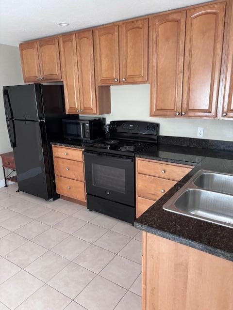 A kitchen features light wood cabinets, black appliances, and dark granite countertops — 5393 SE 48th Avenue Unit C, Stuart FL 34997, STUART, FL