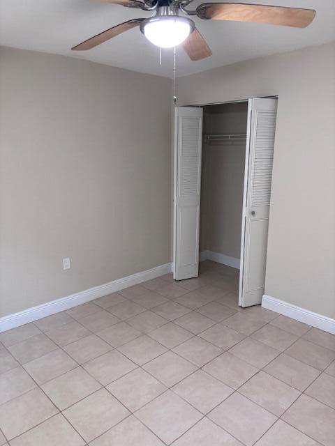 A bedroom with beige walls, tiled flooring, a ceiling fan, and an open closet — 5393 SE 48th Avenue Unit C, Stuart FL 34997, STUART, FL