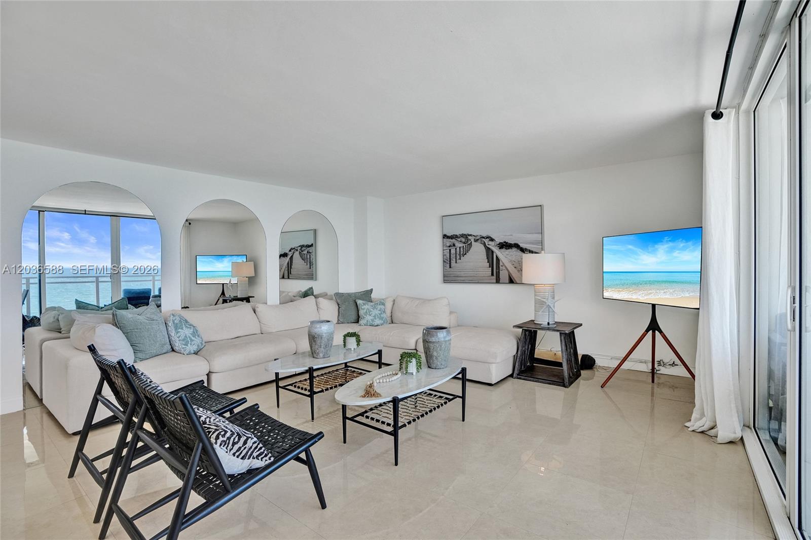 A bright living room features a white sectional sofa, arched mirrors, and a tripod television — 2030 S Ocean Dr # 821, Hallandale Beach FL 33009, HALLANDALE BEACH, FL
