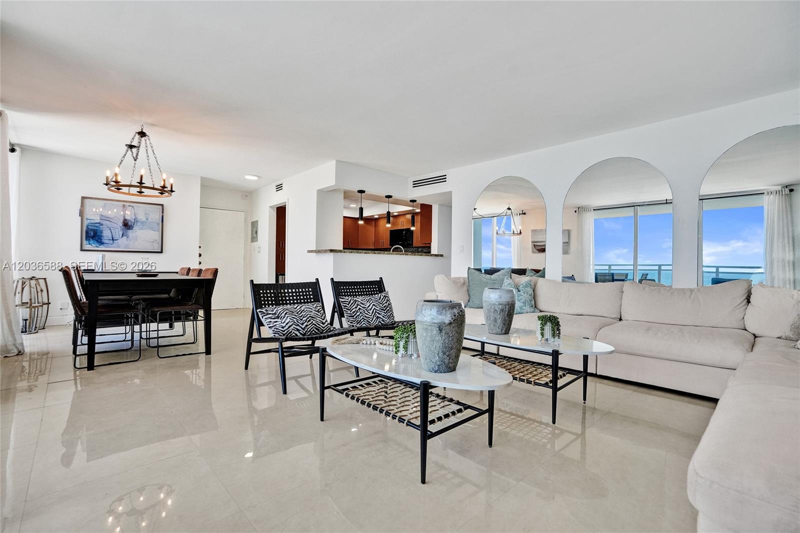 A bright living and dining area features white tile floors, arched mirrors, and ocean views — 2030 S Ocean Dr # 821, Hallandale Beach FL 33009, HALLANDALE BEACH, FL