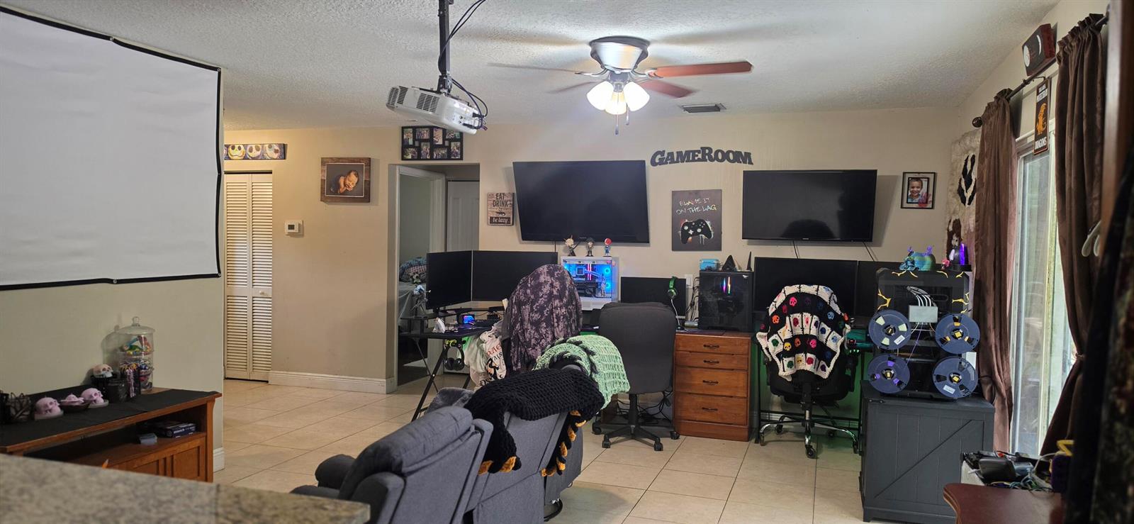 A game room featuring two computer desks, multiple wall-mounted televisions, a projector screen, and tile flooring — 15779 77th Place N, Loxahatchee FL 33470, LOXAHATCHEE, FL