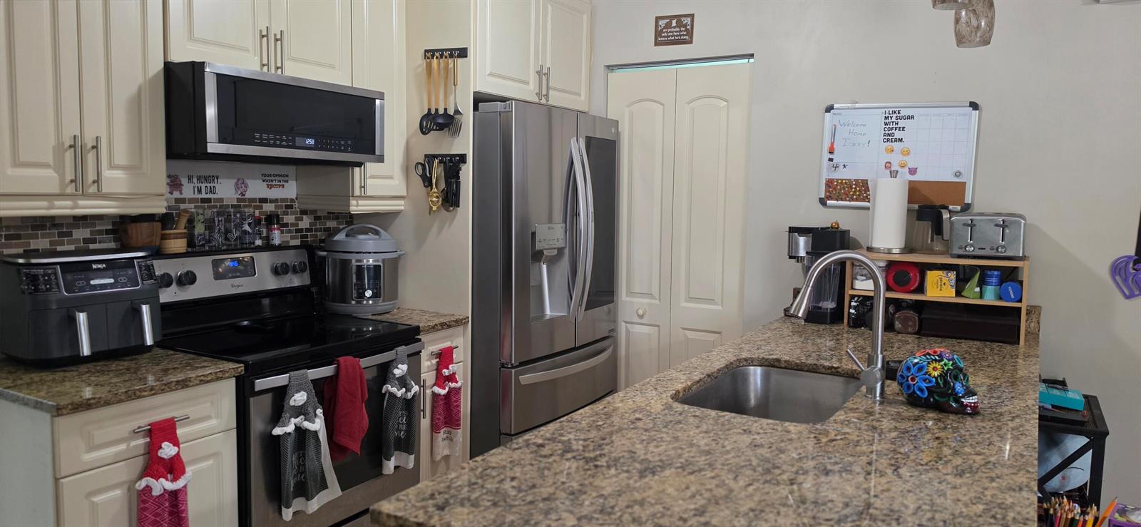 A kitchen features cream cabinets, granite countertops, stainless steel appliances, and a central island sink — 15779 77th Place N, Loxahatchee FL 33470, LOXAHATCHEE, FL