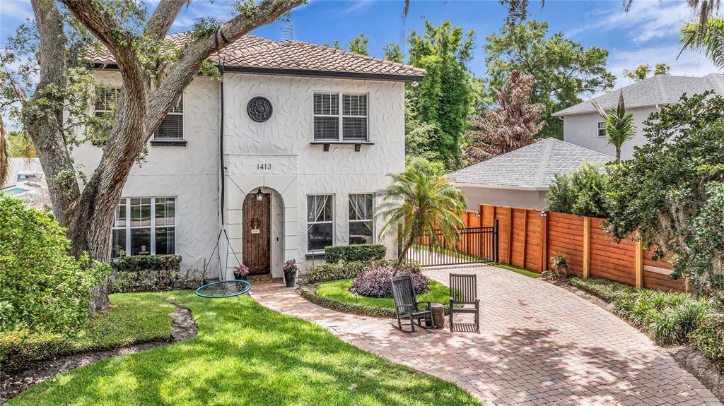 A two-story stucco house with a brick driveway, a front lawn, and a wooden fence — 1413 OSCEOLA COURT, ORLANDO, FL