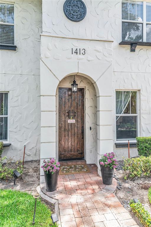 A textured white exterior features a wooden arched front door and a brick walkway — 1413 OSCEOLA COURT, ORLANDO, FL