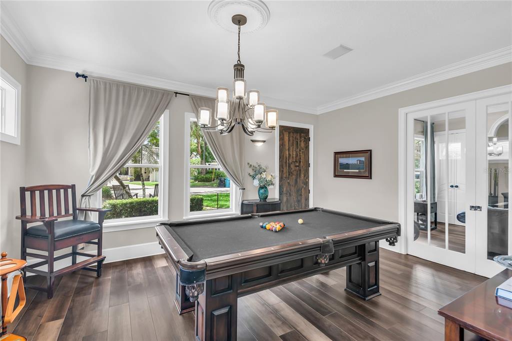 A game room features a pool table, dark wood flooring, and a chandelier under crown molding — 1413 OSCEOLA COURT, ORLANDO, FL