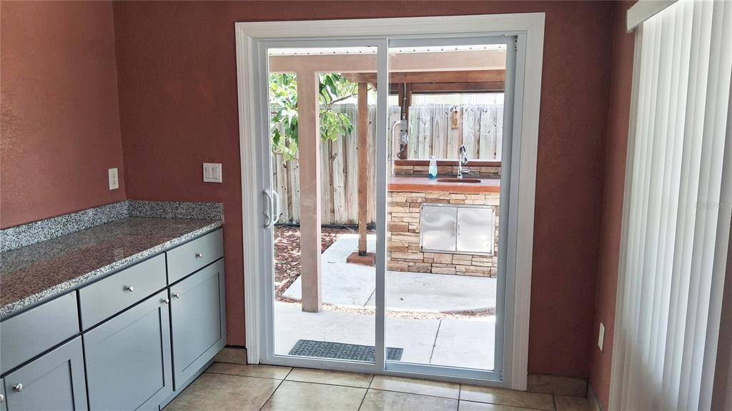 A kitchen with gray cabinets and granite countertops looks out through sliding doors to a patio — 7322 TANGELO AVENUE, PORT RICHEY, FL