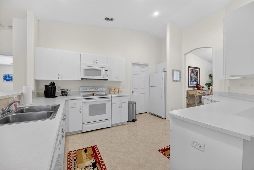 A kitchen with white cabinets, white appliances, and light-colored countertops — 6032 SW 103RD LOOP, OCALA, FL
