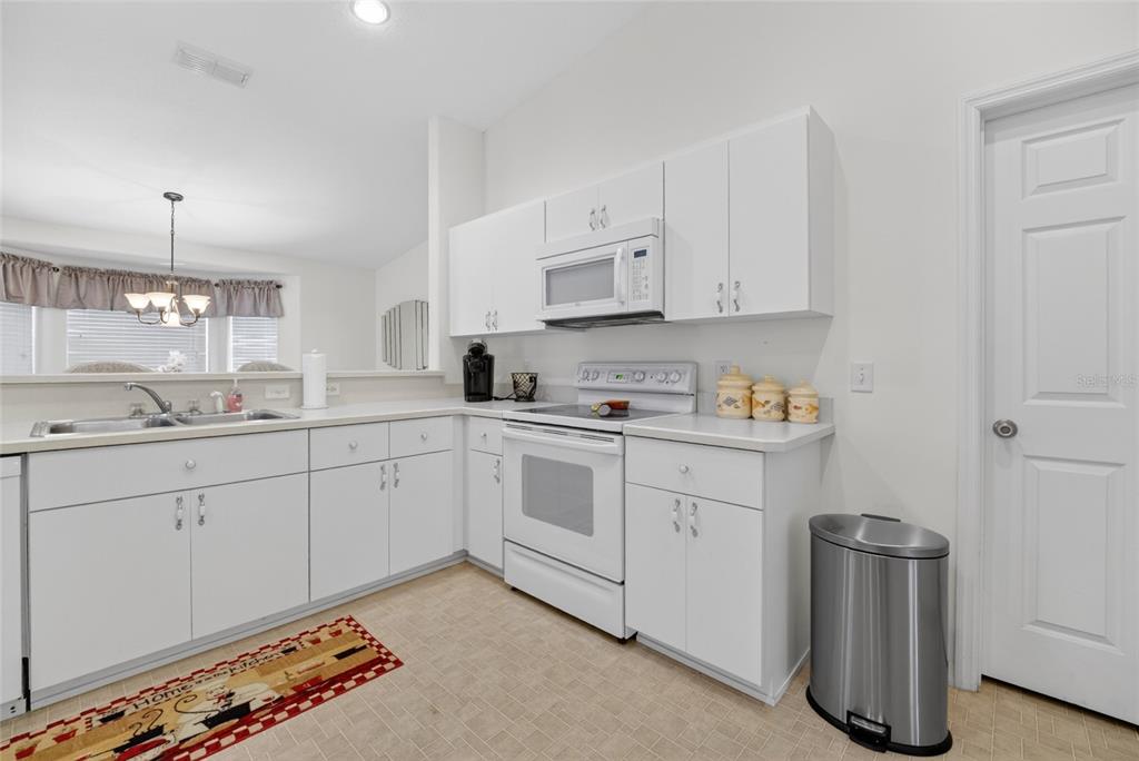 A kitchen features white cabinets, white appliances, and a stainless steel trash can — 6032 SW 103RD LOOP, OCALA, FL