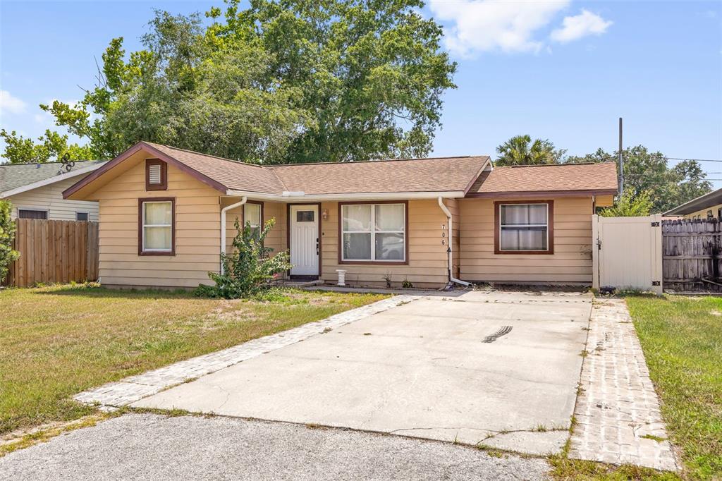 A single-story tan house with a brown roof and a concrete driveway — 706 JERSEY AVENUE, ST CLOUD, FL