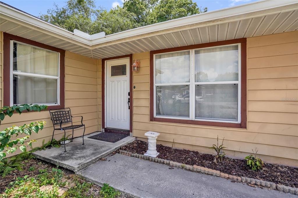 A tan house exterior features a white front door, a concrete porch, and two windows — 706 JERSEY AVENUE, ST CLOUD, FL