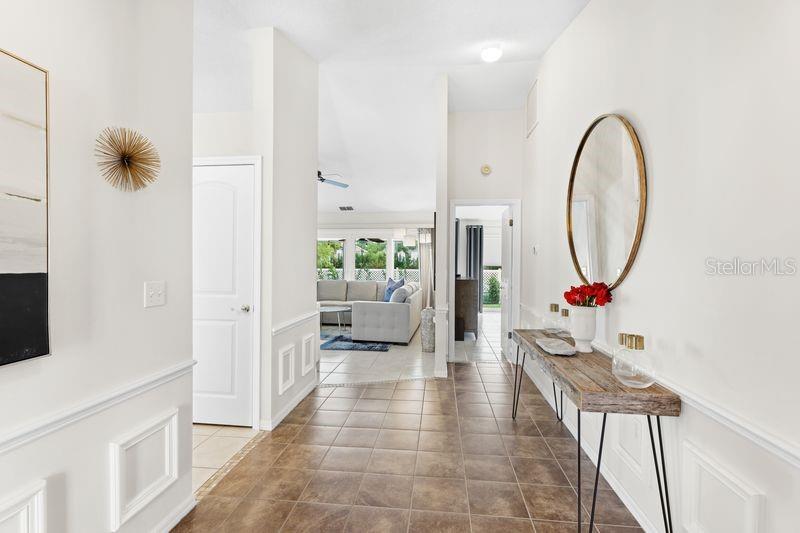 A tiled entryway features a wooden console table, a round mirror, and white wainscoting — 4718 61ST AVENUE TERRACE W, BRADENTON, FL