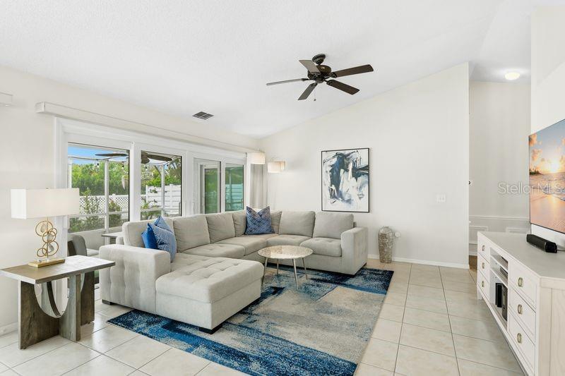 A living room features a light gray sectional sofa, a blue patterned rug, and tile flooring — 4718 61ST AVENUE TERRACE W, BRADENTON, FL