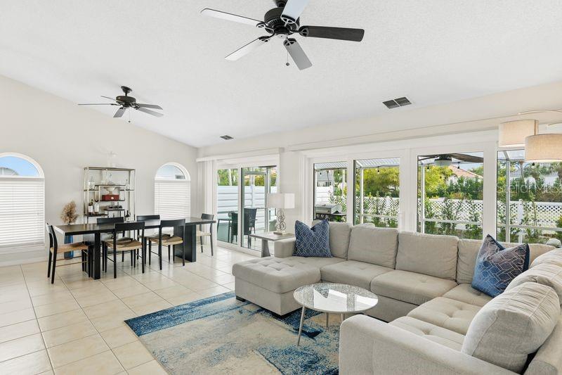 A living and dining area with tile floors, a sectional sofa, and sliding glass doors — 4718 61ST AVENUE TERRACE W, BRADENTON, FL