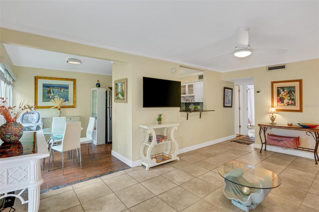 A living room with tile flooring, a wall-mounted television, and an adjacent dining area — 3413 CLARK ROAD UNIT 114, SARASOTA, FL