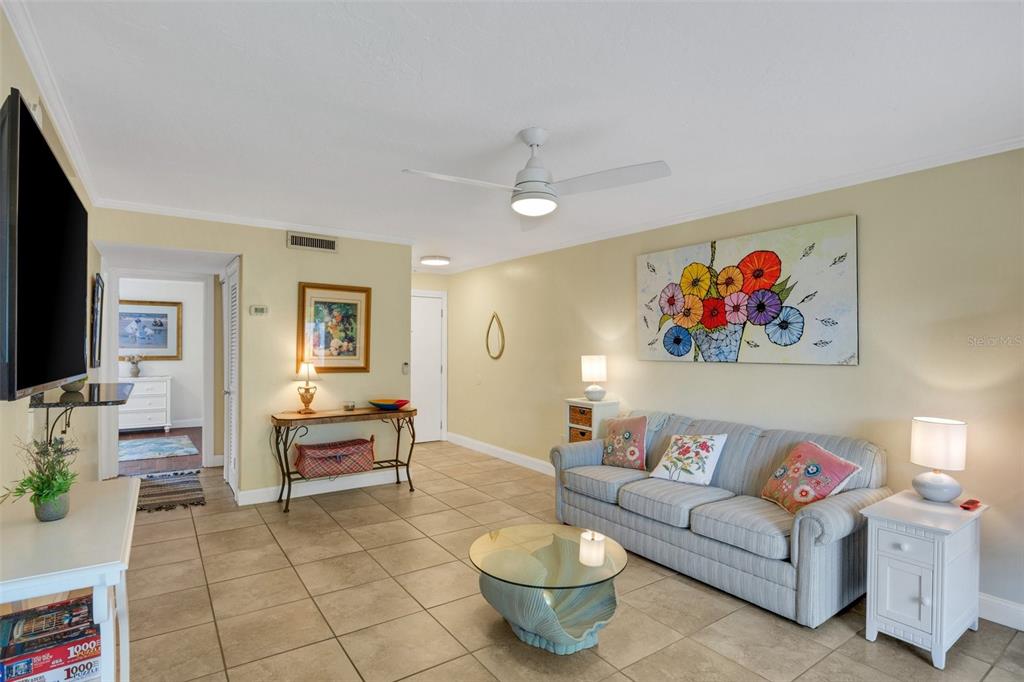 A living room features tile flooring, a blue striped sofa, and a ceiling fan — 3413 CLARK ROAD UNIT 114, SARASOTA, FL