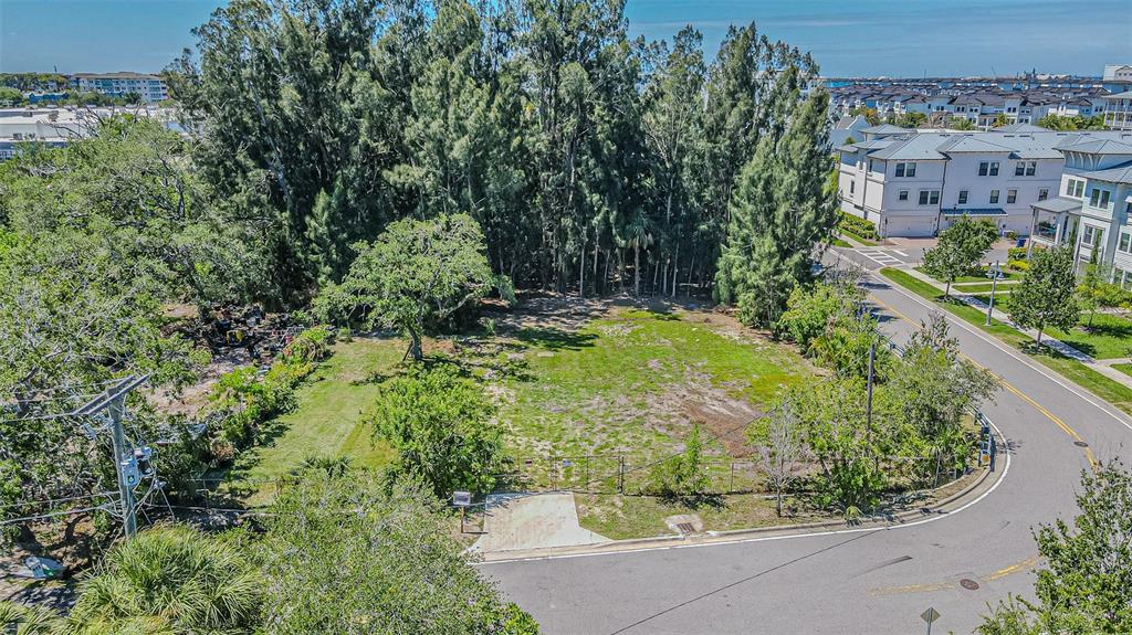 An aerial view shows a vacant, fenced corner lot bordered by trees and residential streets — 4904 W PAUL AVENUE, TAMPA, FL