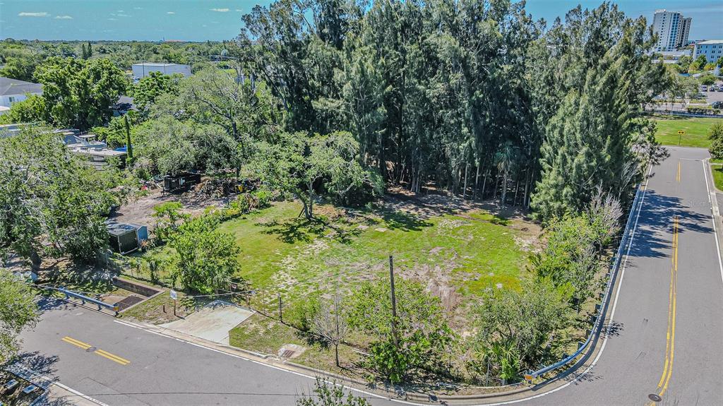 An aerial view of a vacant, grassy corner lot surrounded by trees and paved roads — 4904 W PAUL AVENUE, TAMPA, FL