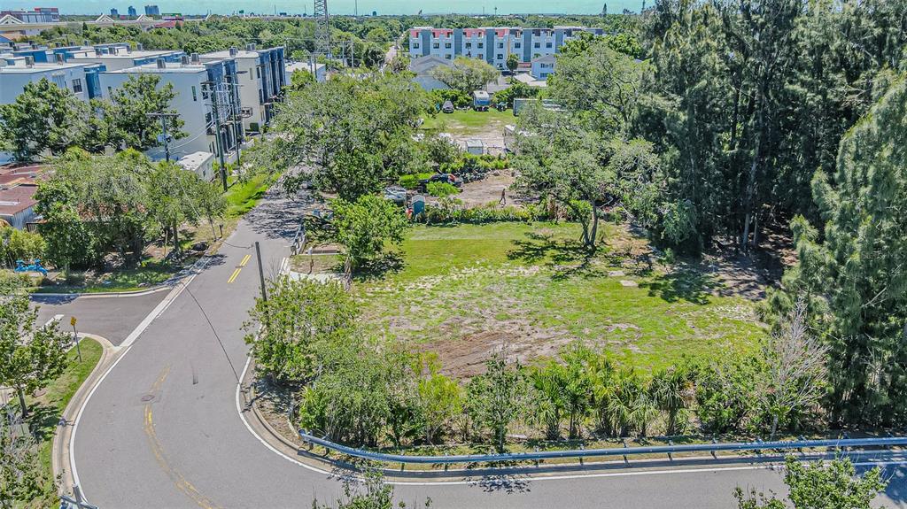 An aerial view shows a vacant, grassy lot bordered by a curved road and trees — 4904 W PAUL AVENUE, TAMPA, FL