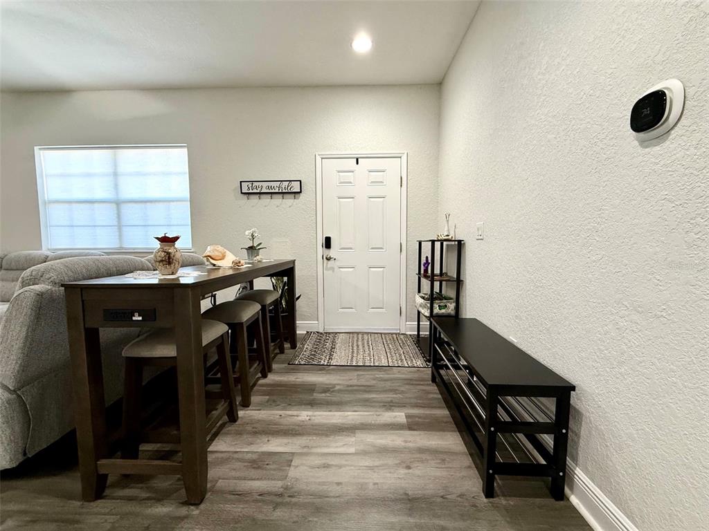 An entryway features a console table with stools, a shoe bench, and a front door — 17411 PROMENADE DRIVE, CLERMONT, FL